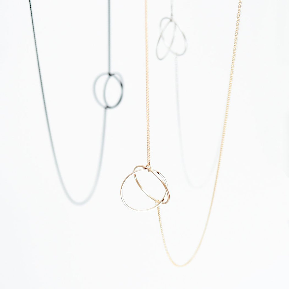 
                  
                    This simple geometric lariat necklace can be worn flat against the body or with the circle charms pulled together for a more three-dimensional look
                  
                