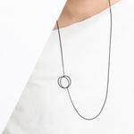 This simple geometric lariat necklace can be worn flat against the body or with the circle charms pulled together for a more three-dimensional look